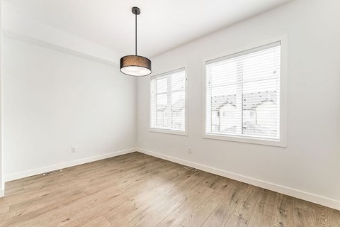 an empty living room with wood floors and two windows