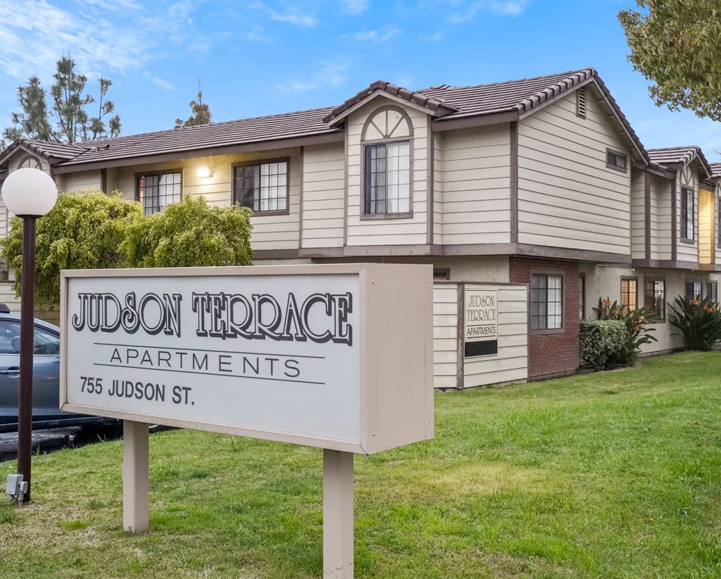 A sign for Judson Terrace Apartments stands in front of a building.