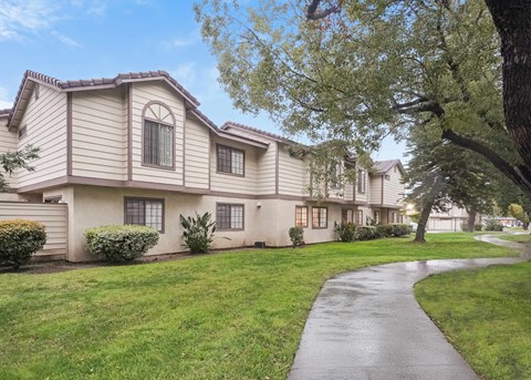 A residential building with a well-maintained lawn and a paved walkway.