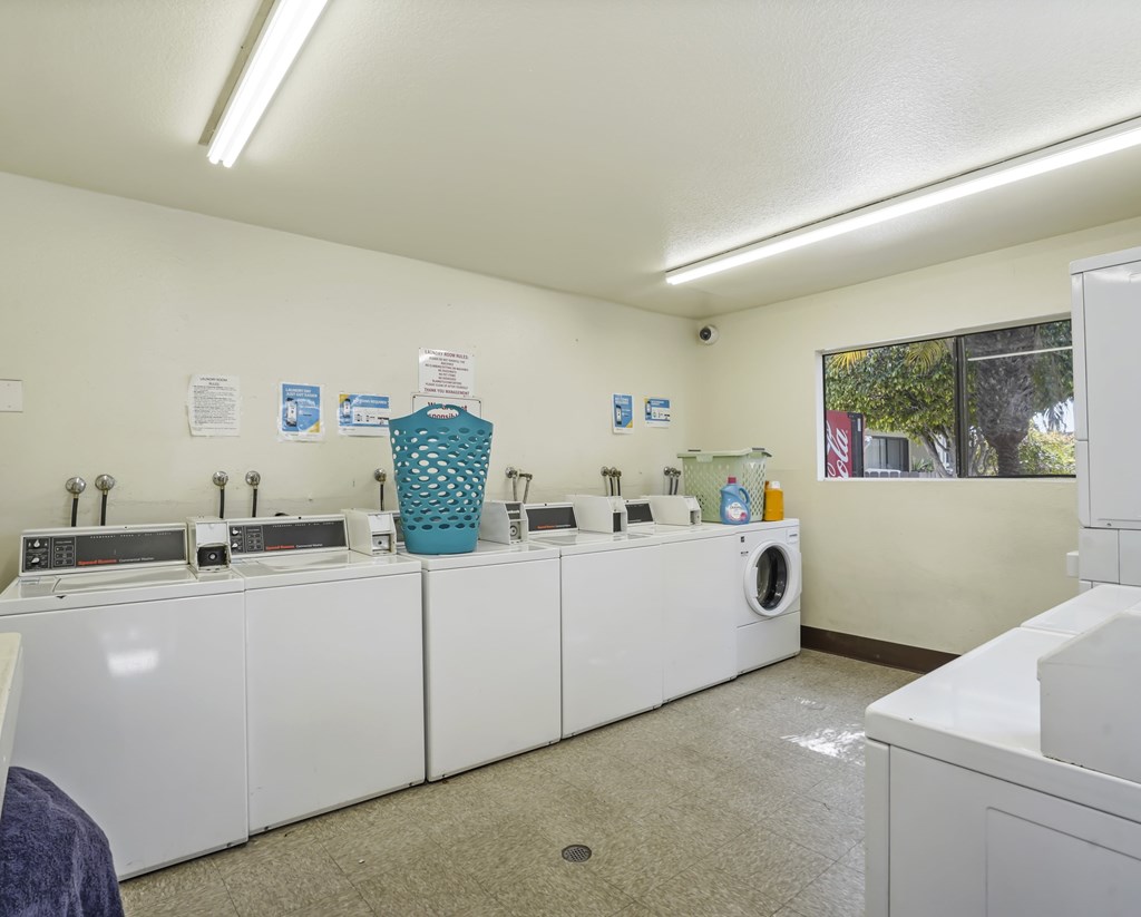 A laundromat with washers and dryers and a basket of laundry detergent.
