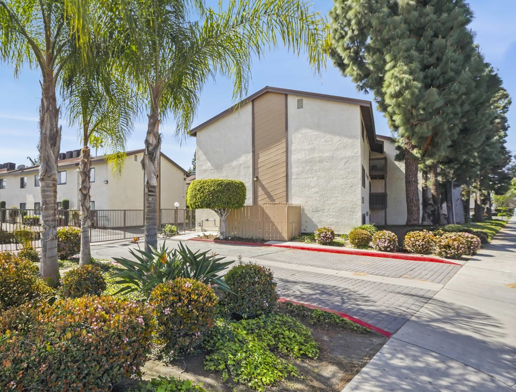A modern building with a grey exterior is surrounded by greenery and trees.