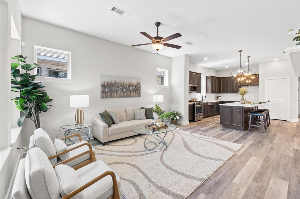 A modern living room with a white sofa, a glass coffee table, and a ceiling fan.