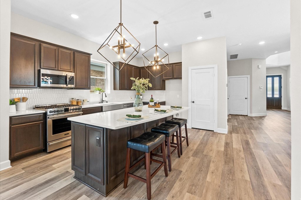 A kitchen with a white island and dark brown cabinets.