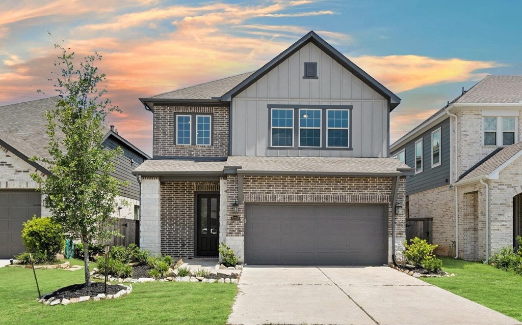 A house with a garage and a tree in front.