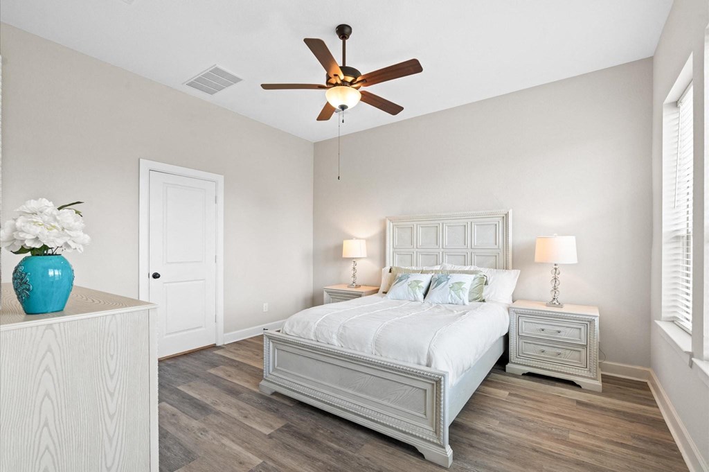 A bedroom with a bed, nightstands, and a ceiling fan.