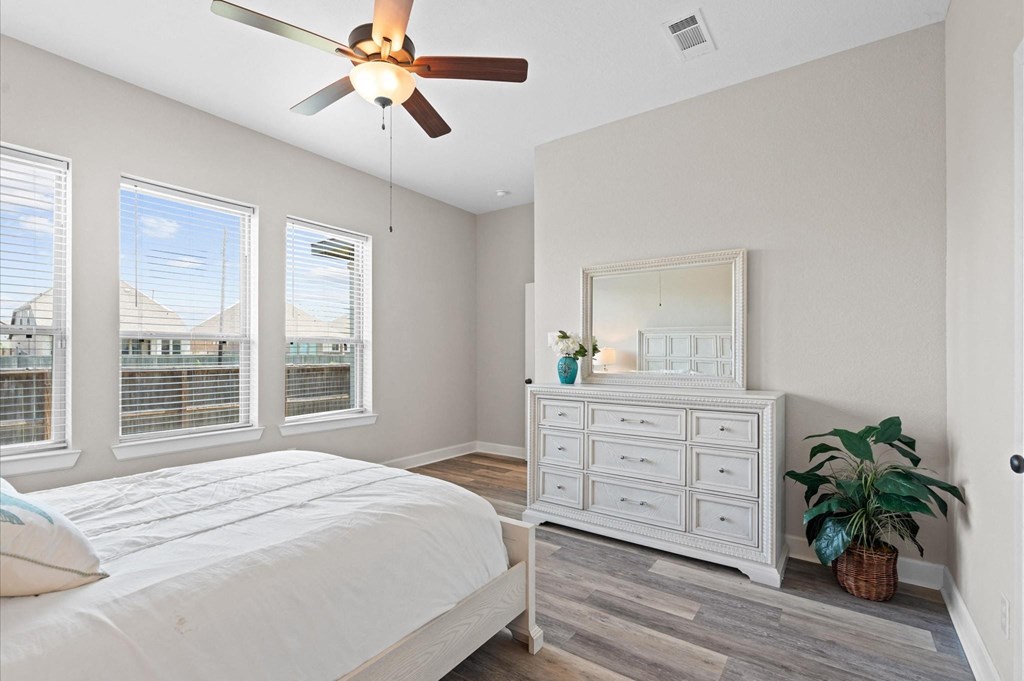 A bedroom with a bed, dresser, and a ceiling fan.