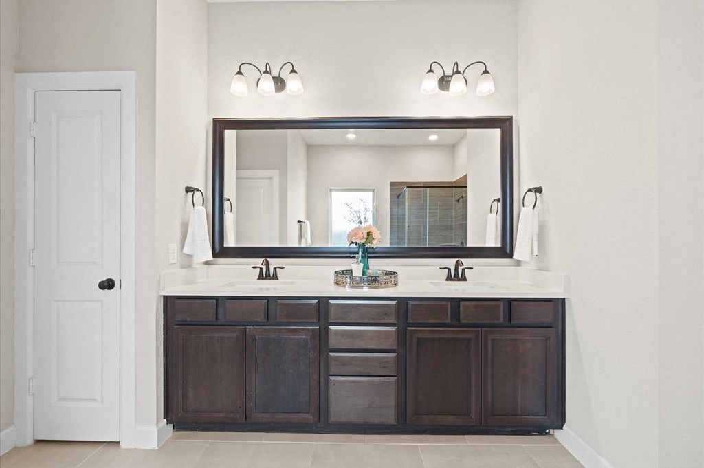 A bathroom with a large mirror above a vanity with two sinks.