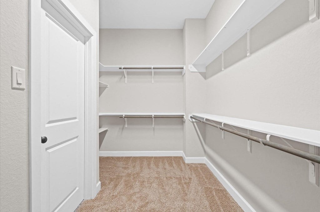 A white door is open to a room with a carpeted floor and a wall-mounted shelf.