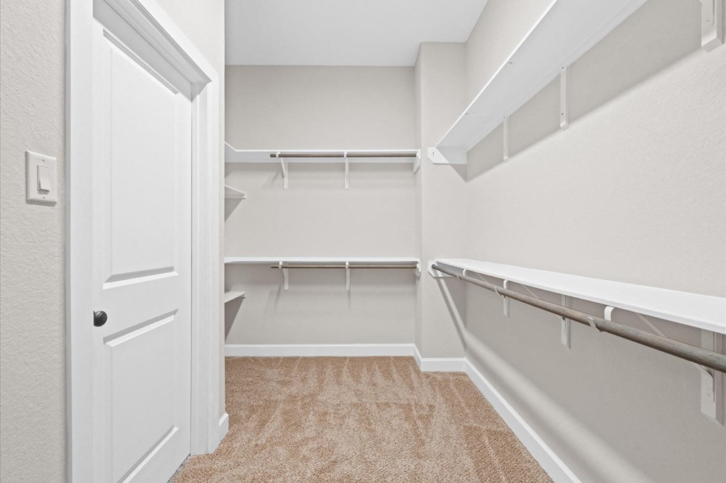 A white door is open to a room with a carpeted floor and a wall-mounted shelf.