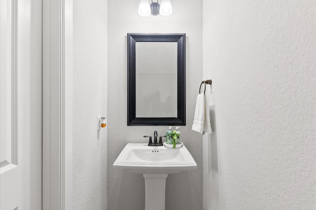 A bathroom with a white sink and a mirror above it.