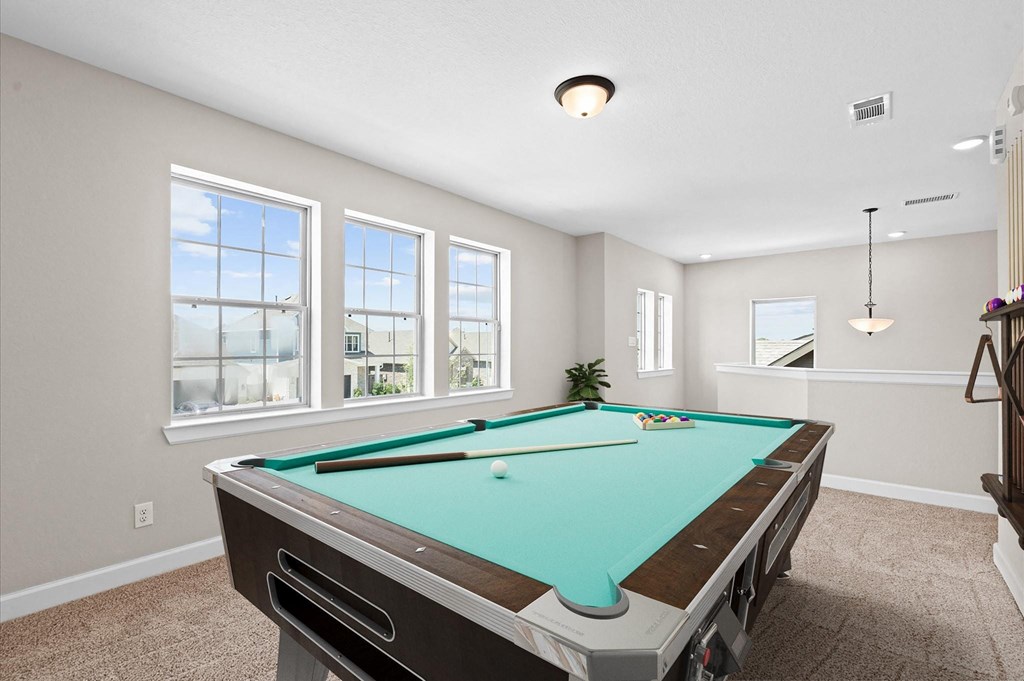 A pool table in a room with a carpeted floor and a window.