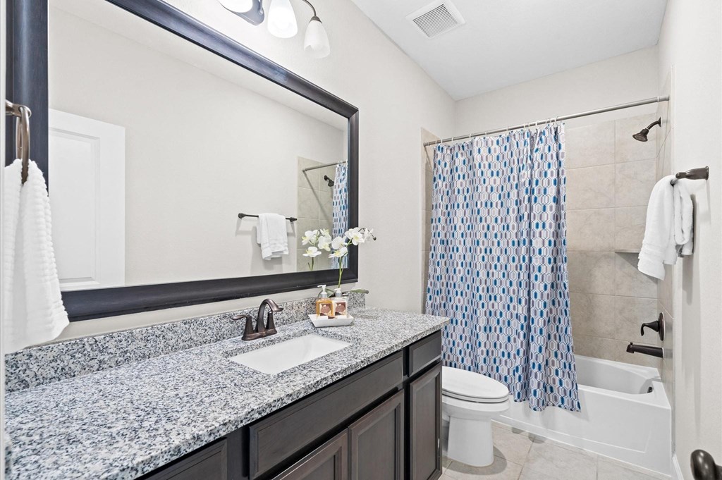 A bathroom with a sink, mirror, toilet, and shower.