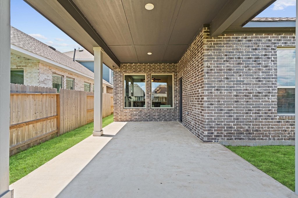 A covered walkway leads to a brick building with a glass door.