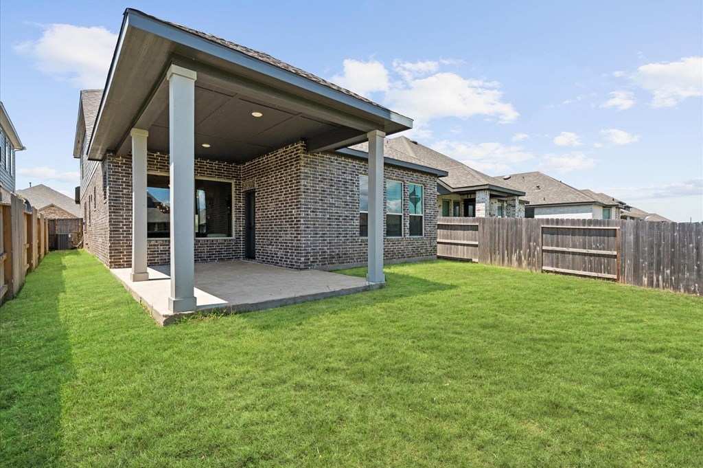 A house with a covered patio and a green lawn.