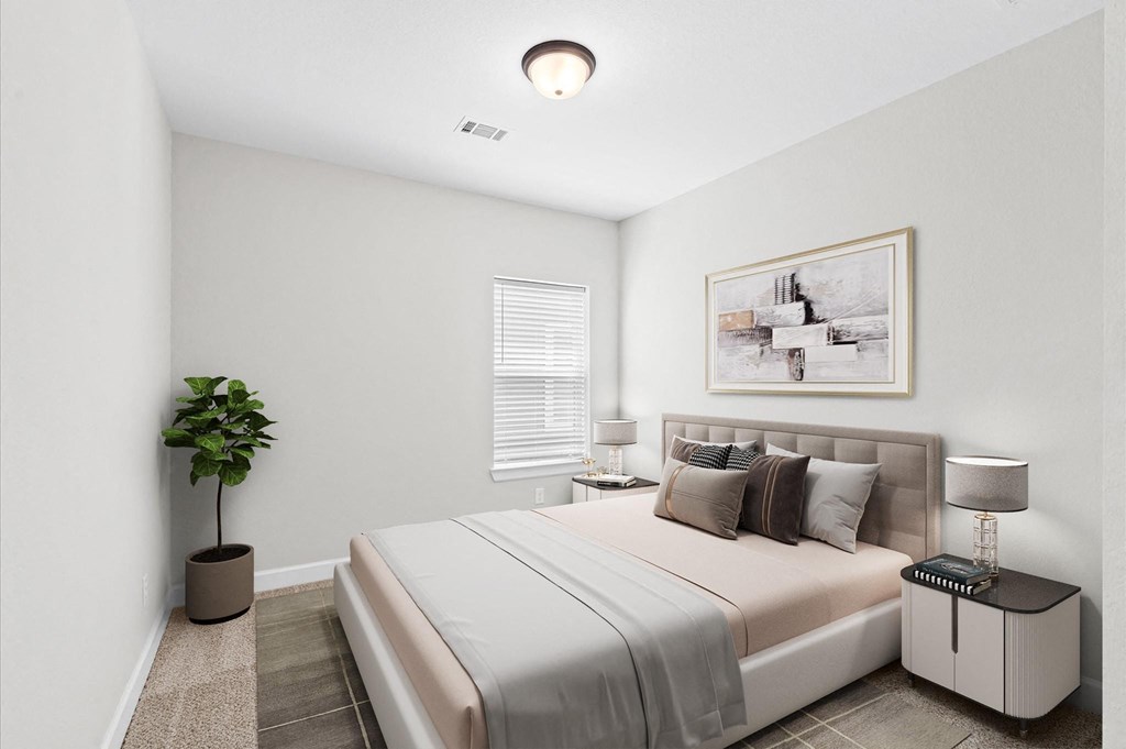 A bedroom with a bed, nightstand, and a plant.