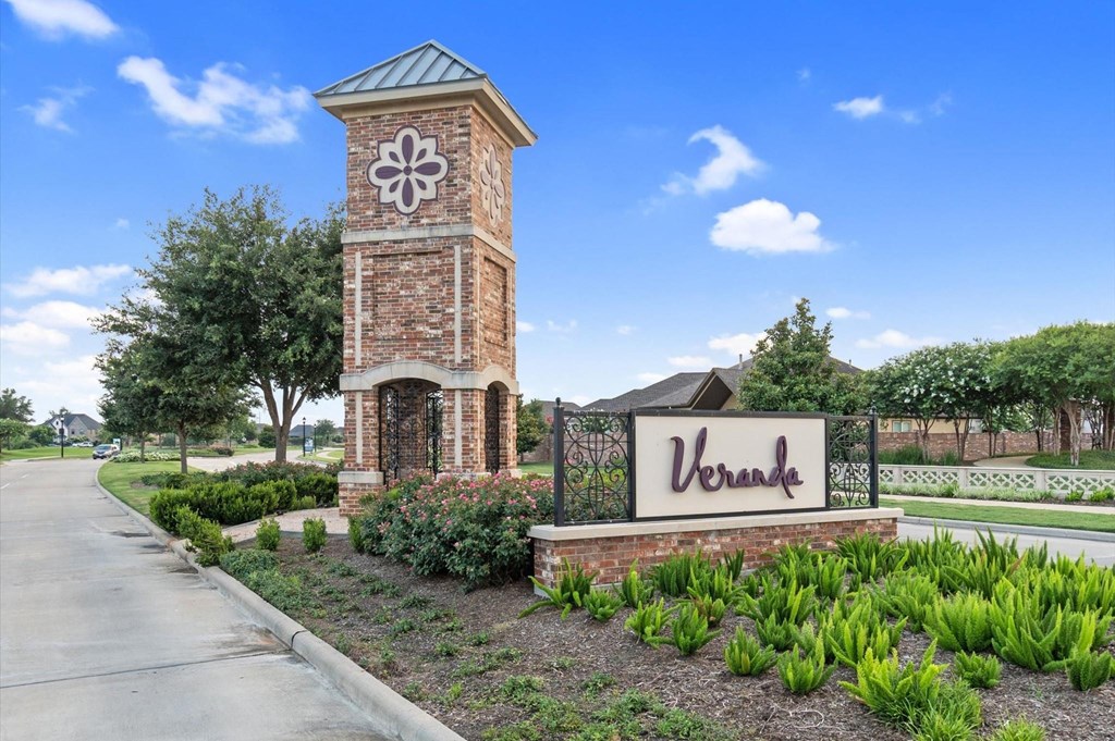 A brick clock tower stands in front of a Veranda sign.