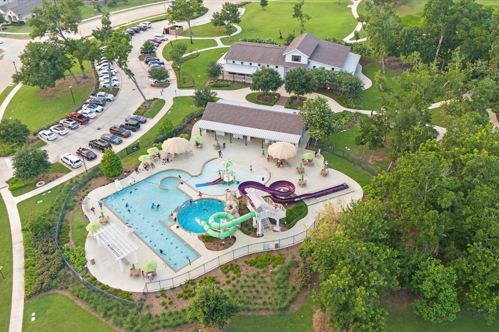 An aerial view of a park with a playground, a swimming pool, and a building.