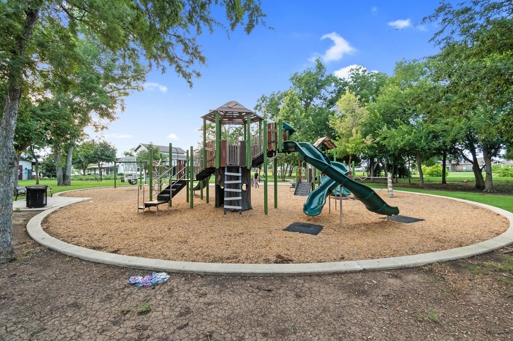 A playground with a green slide and a brown sandy area.
