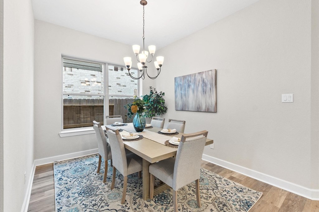 A dining room with a table set for two and a chandelier hanging from the ceiling.