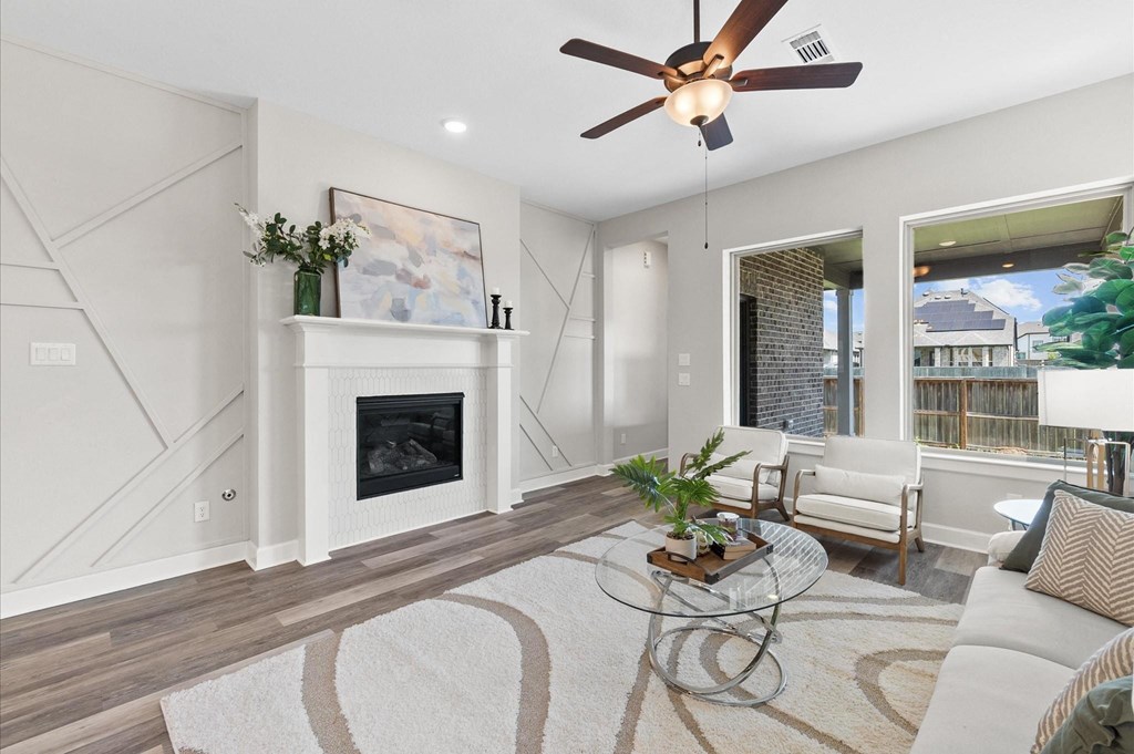 A modern living room with a fireplace and a ceiling fan.