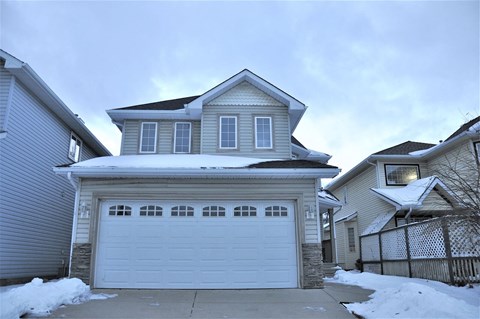 A house with a garage and a driveway covered in snow.