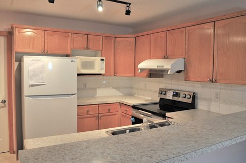 A kitchen with a white fridge, microwave, and stove top oven.