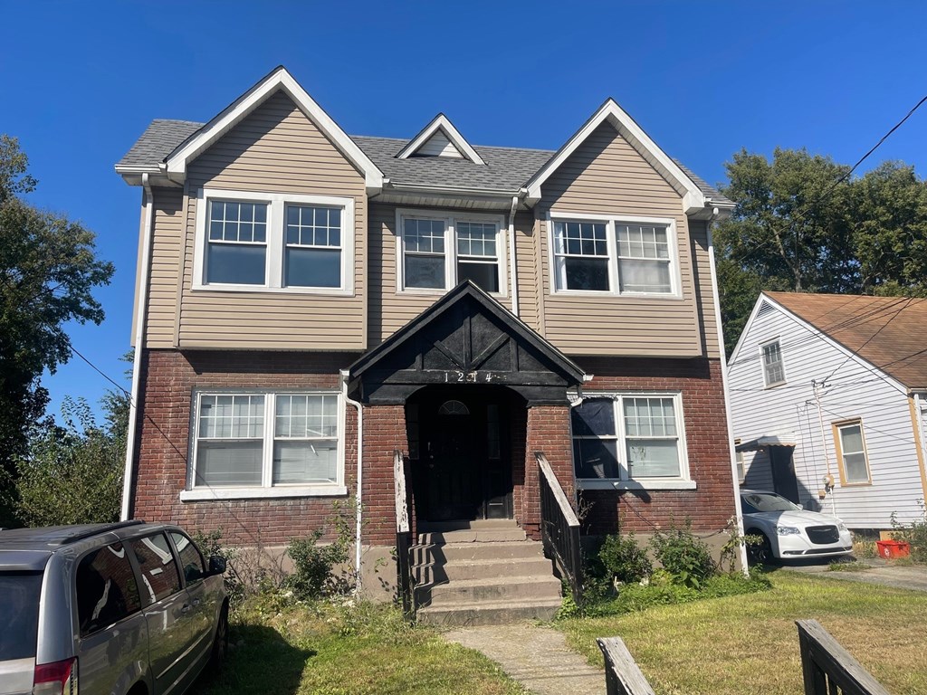 A two-story house with a grey roof and a black front door.