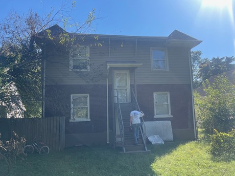 A man is painting the exterior of a house.