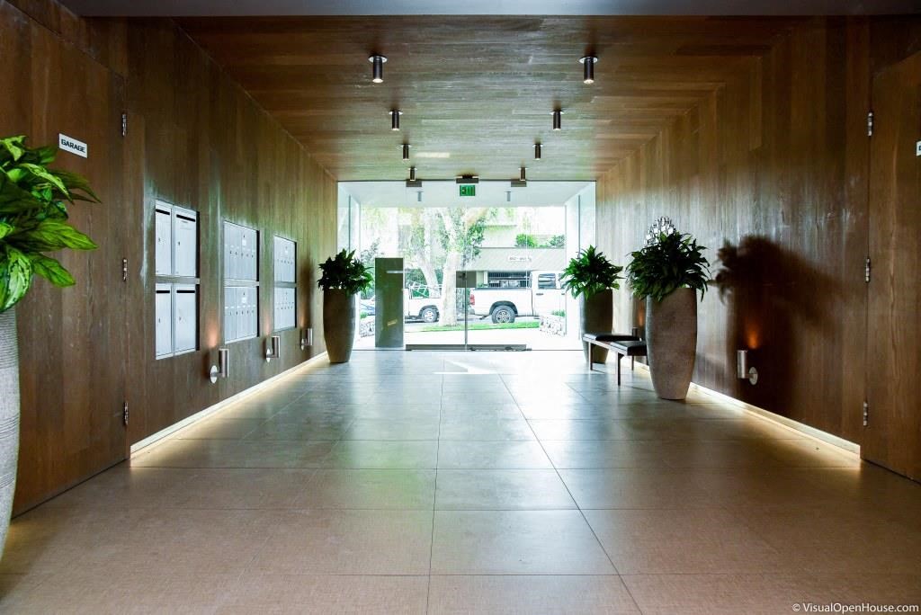 a long hallway with plants and a large glass door