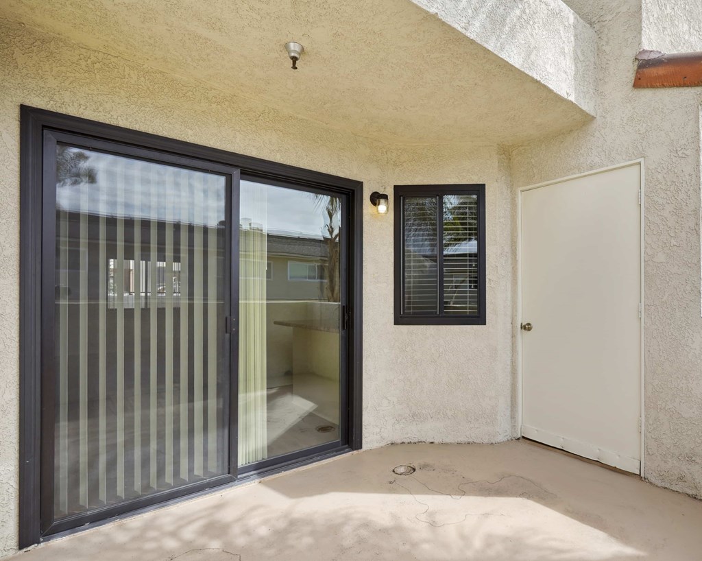 A patio with a sliding glass door and a white door.