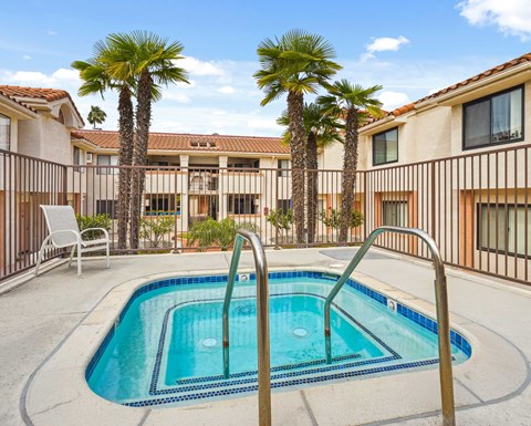A pool surrounded by palm trees and a white chair.