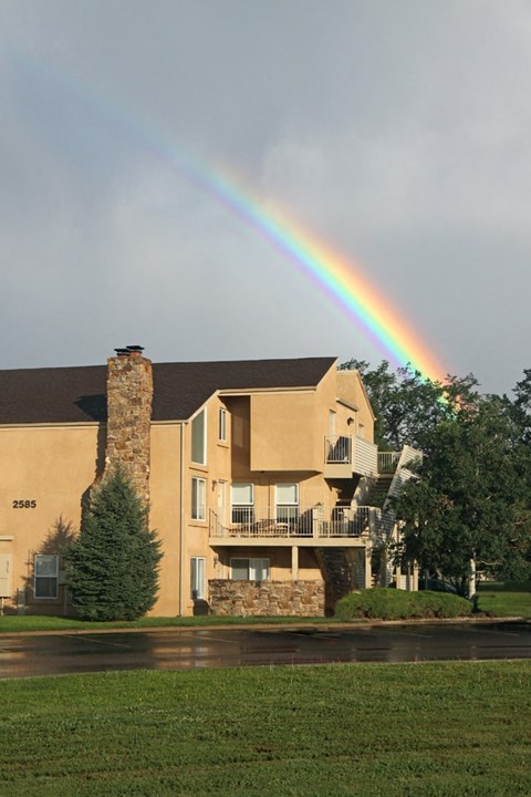 A rainbow appears over a large house with the number 2585 on it.