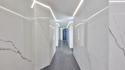 a long white hallway with white marble walls and a blue door