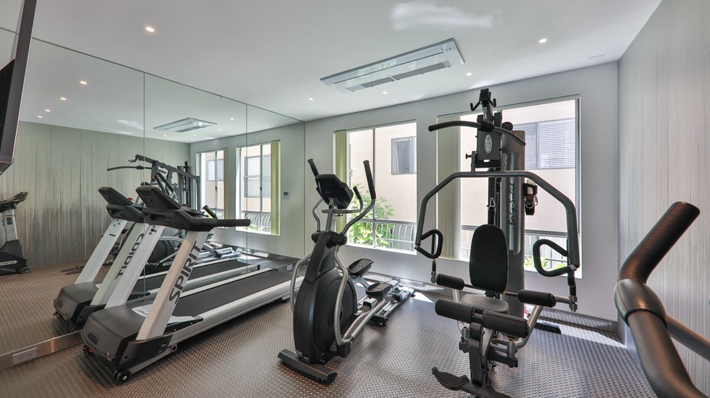 a gym with treadmills and other exercise equipment in a glass walled room