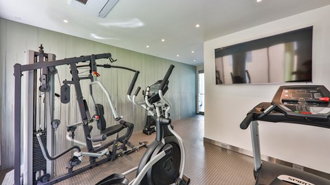 a gym with exercise equipment and a tv on the wall