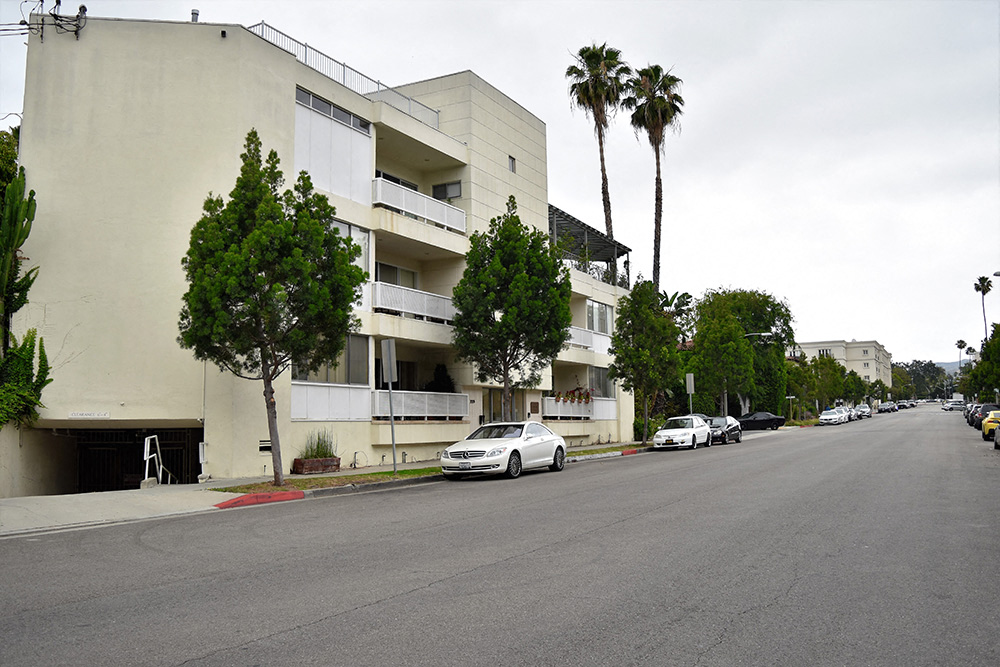 an apartment building on a street with cars parked in front of it