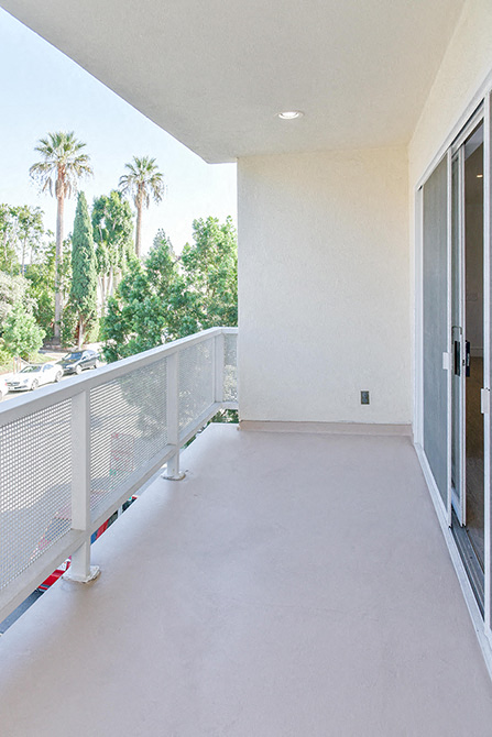 an empty balcony with a door and palm trees
