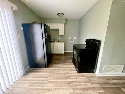 A kitchen with a black fridge and black oven.