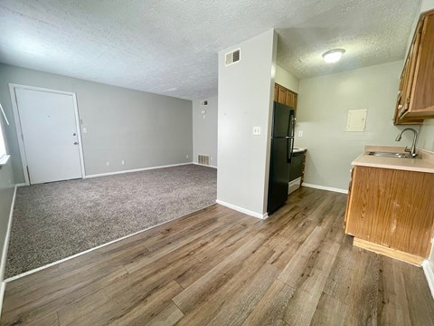 A kitchen area with a refrigerator, sink, and cabinets.