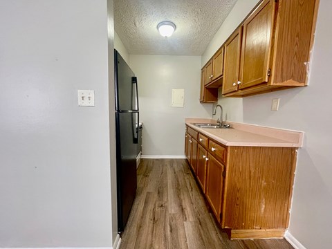 A kitchen with wooden cabinets and a black refrigerator.