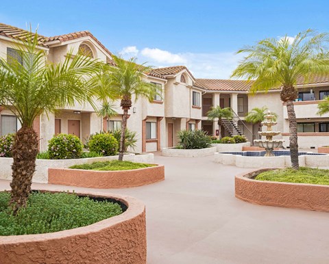 A large building with a courtyard and palm trees.