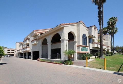 A building with a red tile roof and palm trees in front.
