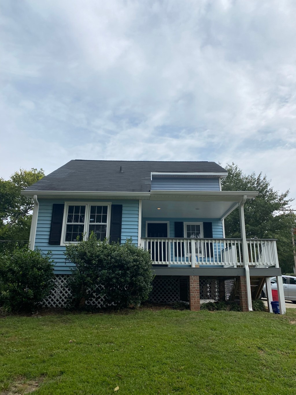 a blue house with a white porch and a cloudy sky
