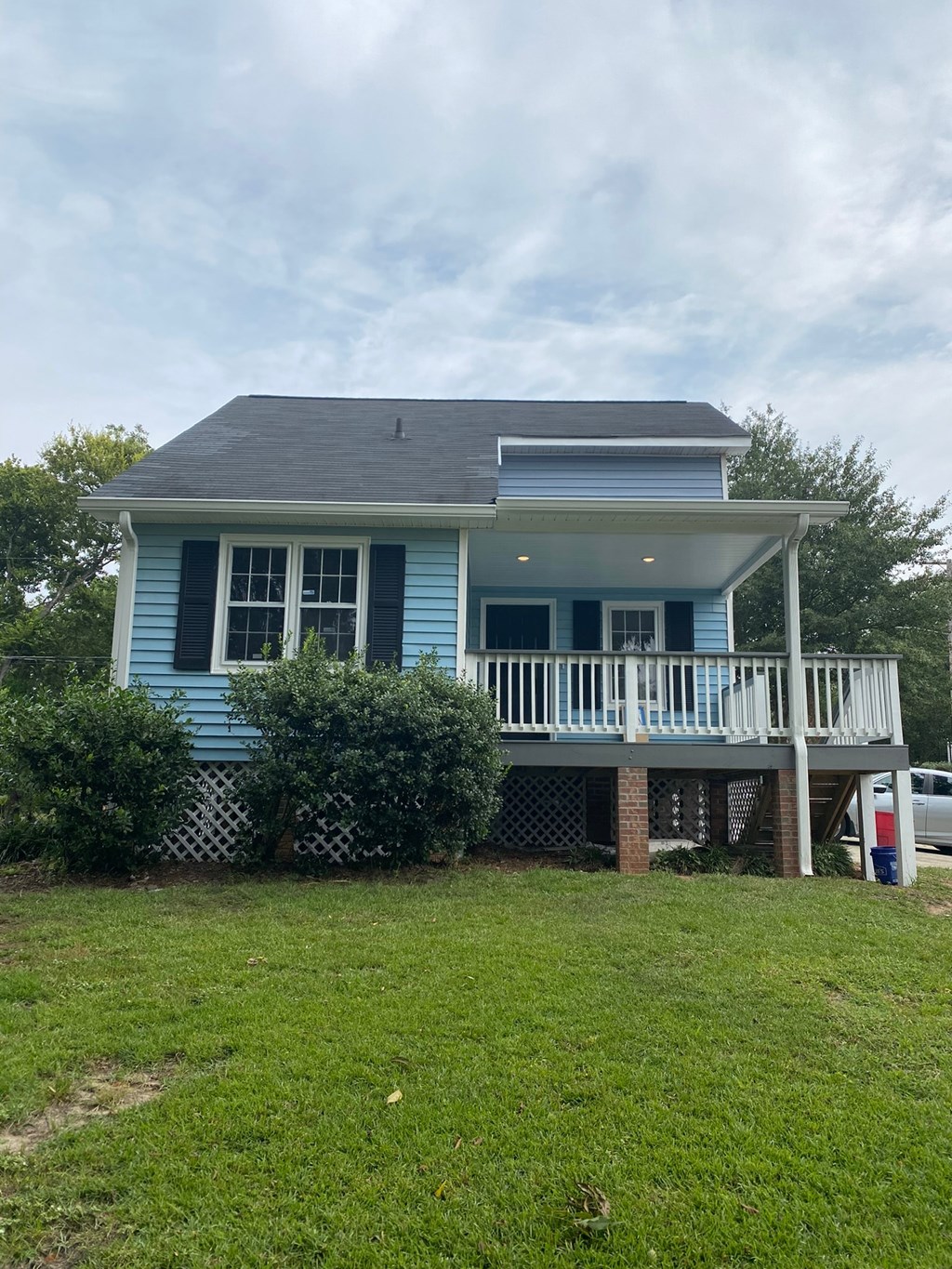 a blue house with a white porch and a lawn