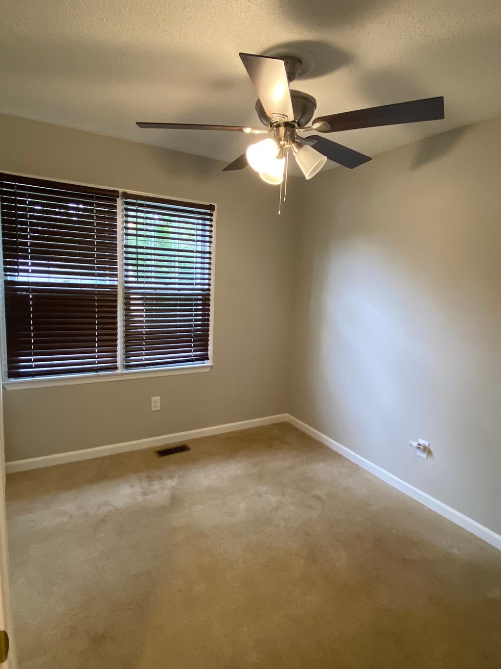 an empty room with a ceiling fan and a window
