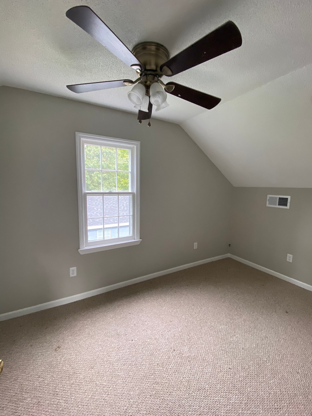 an empty bedroom with a ceiling fan and a window