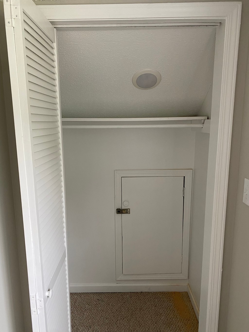 a closet with a white door and a white ceiling and a door to a closet