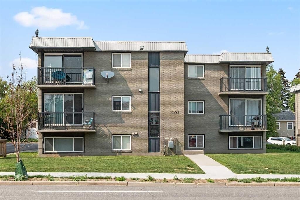 A grey apartment building with a black door and windows.
