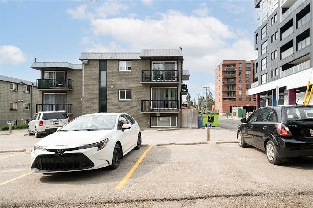 A white car is parked in a parking lot in front of a building.