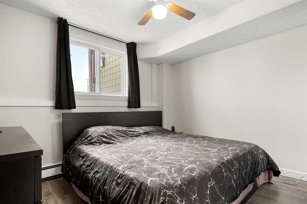 A bedroom with a bed, nightstand, and window with black curtains.